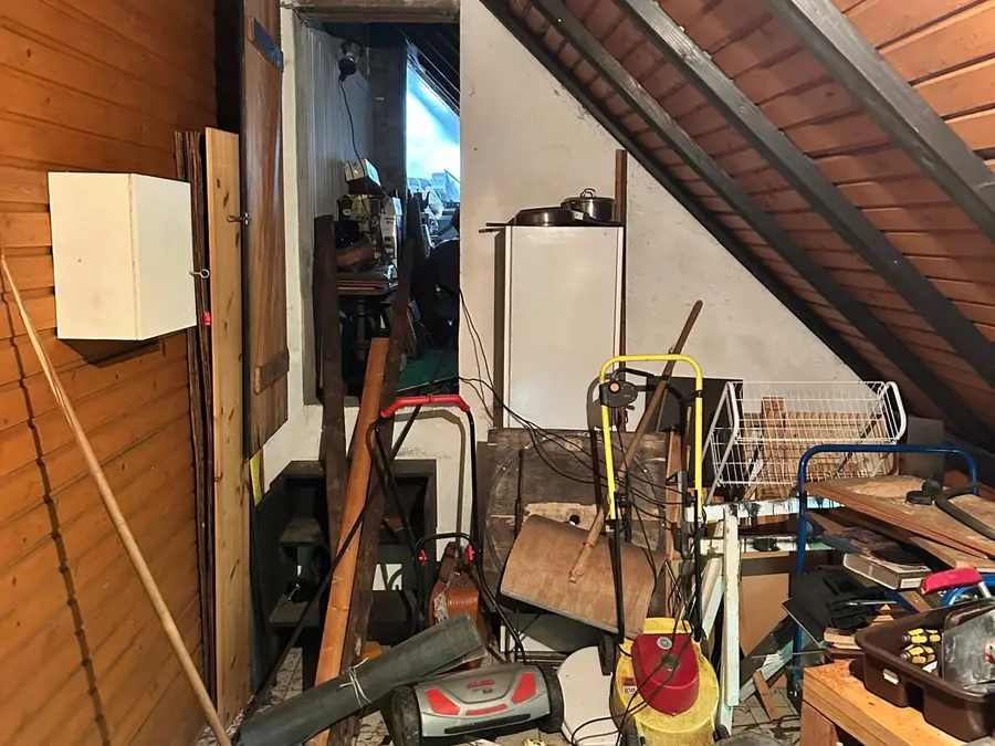 Vollgestellter Dachboden mit Rasenmähern, Holz und Hausrat vor der Entrümpelung